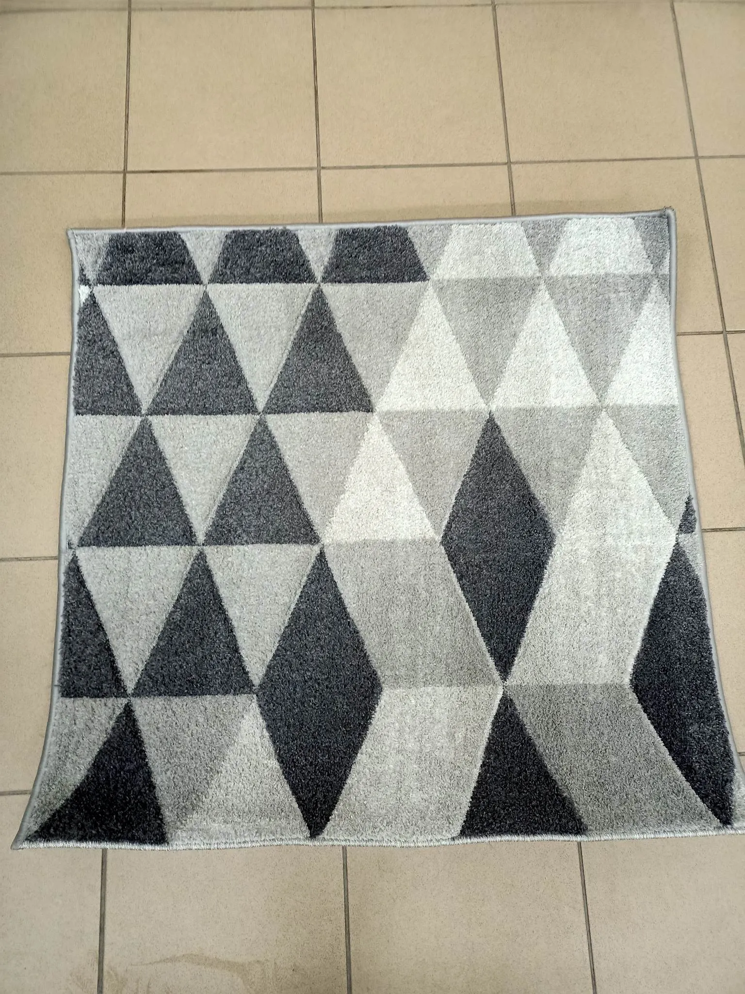 Wyczyszczony dywan w geometryczne wzory, w jasnych, czystych odcieniach szarości